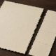 A cream bond torn into a plain principal sheet and a thin coupon strip on a dark wooden desk.